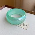 Primer plano detallado de un brazalete ancho verde translúcido con efecto iridiscente - Cian