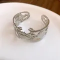 Close-up of silver metal cuff bracelet featuring hollow-out crab and ocean motifs - Silver