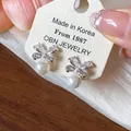 Close-up of butterfly pearl earrings with sparkling zircon inlay on display card - Silver & White (Silver Earring Post)