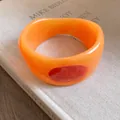 Dettaglio ravvicinato di un bracciale rigido in resina arancione con ovale rosso smaltato - Arancione