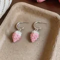 Detail view of sweet pink enamel strawberry pendant earrings on a textured beige tray - Silver Earring Post - Silver - Pink