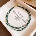 Macro detail of the multi-layered green crystal beaded necklace featuring colorful pearls. - Green