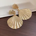 Detailed macro shot of vintage gold pleated shell dangle earrings on wood - Shell Pendant Style (HE33029) / Gold