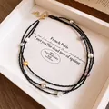 Close-up of a multi-layer black beaded necklace with colorful pearls in a display tray - Black