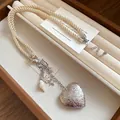 Close-up of ornate silver heart pendant and shell charms on a cream braided rope strap - Silver Heart With White Rope