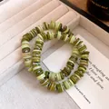 Close-up of green and white shell beaded necklaces on a jewelry tray. - Bracelet / Green