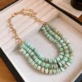 Close-up of multi-layer shell beaded necklace with natural teal disc beads and gold chain - Necklace / Blue