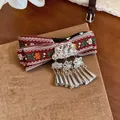 Close-up of vintage Bohemian ribbon hair clip with ethnic tassel details - Red