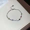 Detail of a sparkling silver bracelet with colorful zircon stones on a beige lining - 1# Bracelet / Silver Multicolor