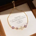 Detail view of a luxury gold zircon bracelet featuring purple floral charms in a box - Style 10 Bracelet / Gold Purple