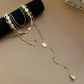 Close-up detail of a layered gold necklace set featuring irregular teardrop charms. - Four-Piece Set / Gold