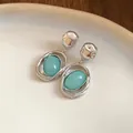 Close-up of retro silver needle earrings with oval sea-foam green acrylic stones - Green