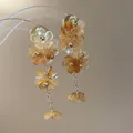 Détail de boucles d'oreilles fleuries ambrées avec chaînes dorées très élégantes - Coffee (Steel Post)