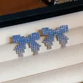 Close-up of elegant blue gradient crystal bow stud earrings on a velvet display - Pixel Bow Style / Blue Gradient
