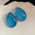 Close-up macro detail of blue resin teardrop earrings with a textured silver-tone frame - Silver-Blue