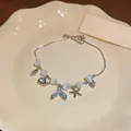 Close-up of elegant mermaid tail and starfish charms on cat-eye stone bracelet - Silver