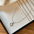 Silver apple pendant with green zircon gemstone displayed in a cream jewelry organizer. - Hollow Apple with Green Zircon Necklace / Silver