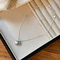 Detailed close-up view of minimalist silver heart necklace with a turquoise bead - Heart and Blue Bead Necklace / Silver