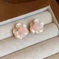 Gros plan détaillé montrant les délicates boucles d'oreilles fleurs en résine à pétales - Fleur / Blanc Cassé