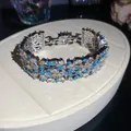 Detailed view of heavy industry silver bracelet with blue and clear zircon floral patterns - Bangle