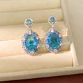 Primo piano di eleganti orecchini ovali in zircone blu in un portagioie di velluto beige - Gioielli con perno in argento / Blu
