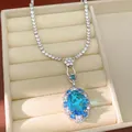 Primo piano di un elegante ciondolo in zircone blu ovale con halo scintillante nel vassoio. - Collana / Argento-Blu