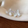Detailed view of elegant flower stud earrings with sparkling zircon and white enamel. - White