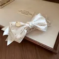 Gros plan sur une pince à cheveux élégante en satin à pois avec breloque dorée - Pince Banane / Blanc
