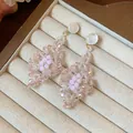 Detalle macro de pendientes de gota de cuentas rosas en forma de rombo en bandeja - Estilo de poste de pendiente de plata / Rosa