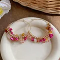 Dettaglio di orecchini a cerchio boho con pietre rosa e arancioni di forma irregolare. - Stile Boho Pietra Multicolore