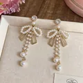 Vue détaillée d'élégantes boucles d'oreilles nœud perle de style français avec cristaux - Style Gland Nœud Strass / Pack de 1 paire / Or Blanc
