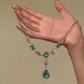 Detailopname van een blauwe kristallen ketting met strass in de hand. - Zilver-Blauwe Waterdruppel