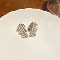 Detailed view of shiny zircon geometric irregular clip-on earrings on a ceramic plate - Irregular Geometric Style / Ear Clip (Pair) / Silver