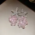 Detail von pinkfarbenen Kristallperlen-Ohrringen mit funkelnden Strassblumen-Steckern. - Rosa