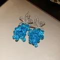 Detailaufnahme von funkelnden blauen Traubenhänger-Ohrringen mit Strassblumen-Elementen. - Blau