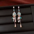 Vista detallada de elegantes pendientes vintage con cuentas turquesas y piedras circón - Dorado/Azul/Café