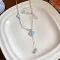 Detailed view of a handmade blue ceramic fish necklace with white dots on a white plate - Blue
