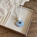 Detail showing the blue wrinkled resin pendant and white cord on a jewelry tray - Blue