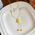 Close-up detail of yellow ceramic fish necklace with lace bow on a white plate - Yellow