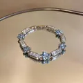 Sparkling silver flower bracelet with blue zirconia stones shown on a mirror surface - Blue / Silver