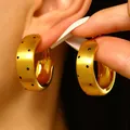 Elegant matte gold brushed hoop earrings featuring black polka dots shown on model ear - Matte Brushed Polka Dot Ring Earrings (3898)