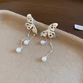 Dettaglio ravvicinato di orecchini a farfalla a pois con eleganti nappe di perle bianche - Bianco con pietre multicolore
