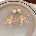 Macro view of vintage gold starfish drop earrings featuring a detailed textured surface - Earrings / Gold