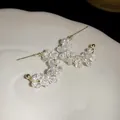 Detailed macro view showing the glass beads and pearl texture of C-shaped earrings - White