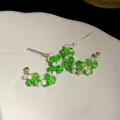 Macro detail of green glass and pearl beaded C-shaped earrings with silver needle posts - Green