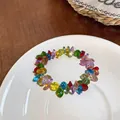 Close-up detail view of a colorful faceted acrylic beaded bracelet on a white ceramic plate - Multicolor