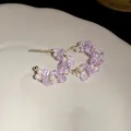 Detail of C-shaped earrings with purple glass beads and white pearls on gold wire. - Purple