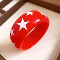 Detailed macro shot of a vibrant red resin bangle featuring white star patterns - Orange