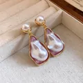 Close-up detail of vintage-style baroque pearl drop earrings with gold framing - Silver Pin-Gold-White