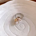 Dettaglio di un anello regolabile argento con conchiglia e perle, design minimalista. - Stile Conchiglia Perla / Argento